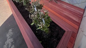 A wooden deck with a planter box containing plants, a folding table, and chairs. - Casa Vento -  Koksijde (Koksijde)