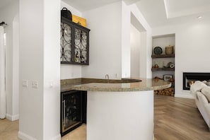 Eine Küche mit Granit-Arbeitsplatte, einem schwarzen Metallschrank mit Glastüren und einem Kamin im Hintergrund.