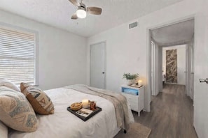 A bedroom with a bed, bedside table, and a ceiling fan. - 2BR • 8 Min Walk to AT&T Stadium • Free Parking (Arlington)