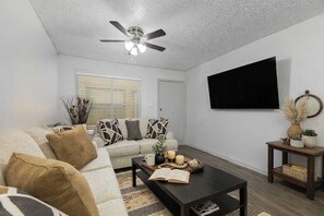 A living room with a sofa, coffee table, and a ceiling fan. - Entertainment District Escape • 2BR + Parking (Arlington)