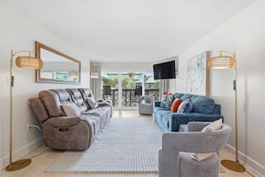 Ein Wohnzimmer mit einer Couch, einem Sessel, einem Couchtisch und einem Fernseher.