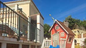Ein Spielplatz mit einer blauen Rutsche und einem roten Spielhäuschen.