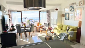 A modern living room with a dining area, a sofa, and a view of the sea. - Las Mimosas 7B Capistrano Village in Nerja (Nerja)