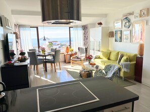 Ein modernes Wohnzimmer mit Essbereich, einer Couch und Meerblick.