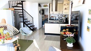 A modern kitchen with a built-in oven, a microwave, and a coffee machine. There is a dining area with a table and chairs, and a staircase leading to an upper level. - Las Mimosas 7B Capistrano Village in Nerja (Nerja)
