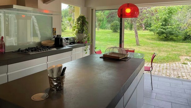 A modern kitchen with a large island, a gas stove, and pendant lighting.
