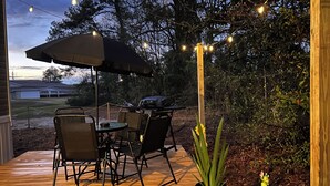 Eine Terrasse im Freien mit Tisch, Stühlen, einem Grill und Lichterketten.
