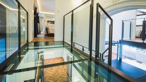A modern hotel corridor with glass railings, a wooden floor, and a view of a bedroom with a bed and a bathroom. - LOFT · KEYWEEK contemporary Loft style Apartment in Biarritz City center (Biarritz)