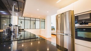 A modern kitchen with a large island, stainless steel appliances, and a view of the living area. - LOFT · KEYWEEK contemporary Loft style Apartment in Biarritz City center (Biarritz)