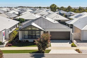 A residential area with modern houses, a well-maintained lawn, and a clear sky. - Coastal Luxe in Seaside Estate | 4 Bedrooms | Walk to Beach (Mandurah)