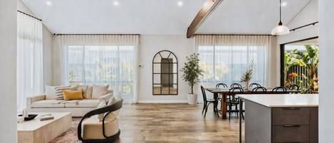 A spacious living area with a sofa, dining table, and kitchen area.