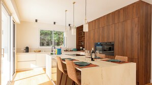 Een moderne keuken met een centraal eiland, houten keukenkastjes en een groot raam.
