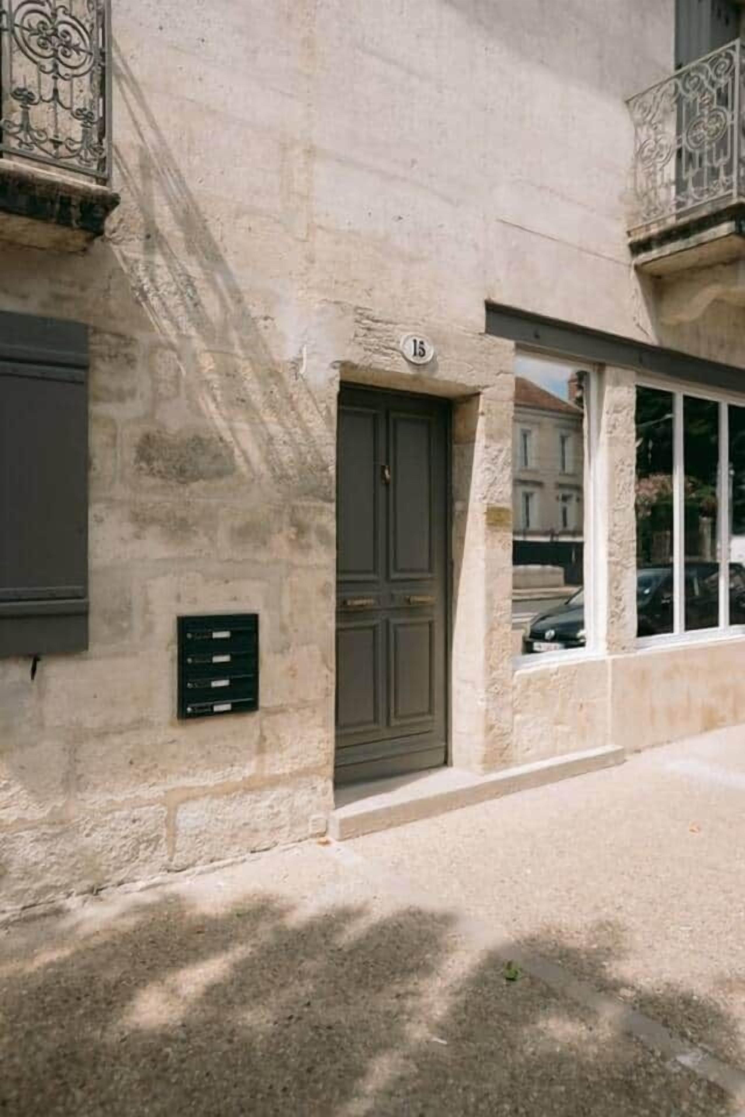 A stone building with a dark door, a window, and a balcony with metal railings.