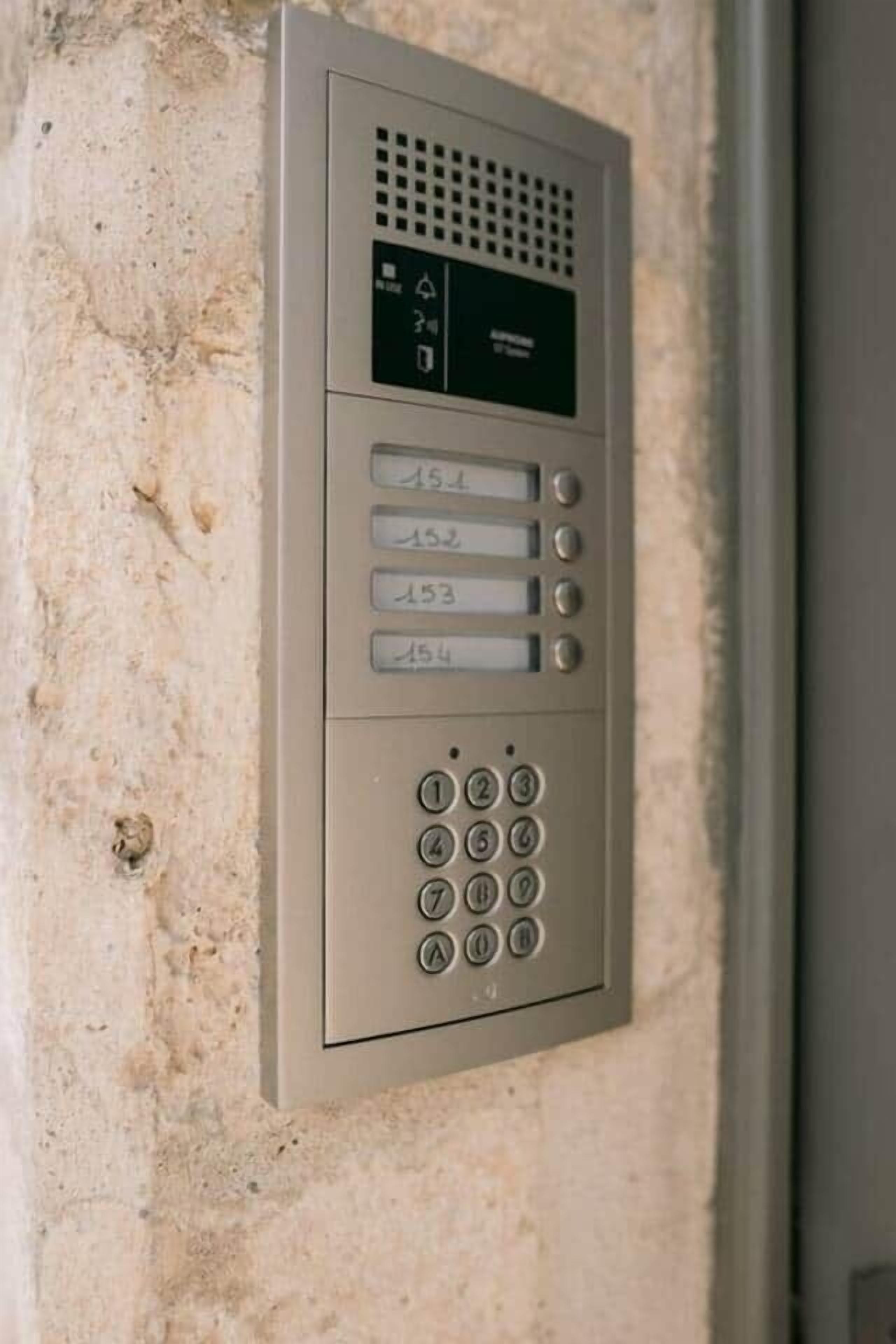 Un système d’interphone mural doté d’un clavier et d’un écran.