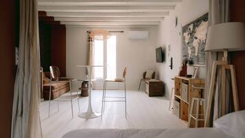 Une pièce comprenant un lit, une table, des chaises, une lampe, un téléviseur et un tableau accroché au mur.