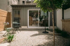 A patio with a table and chairs, a small plant, and a tree. - Georges’ Garden – 151 (Périgueux)