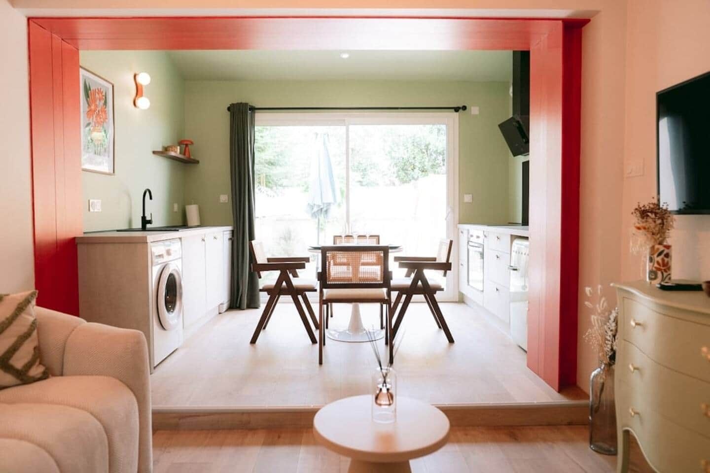 Un espace de vie compact comprenant un coin repas, une kitchenette et un lave-linge.