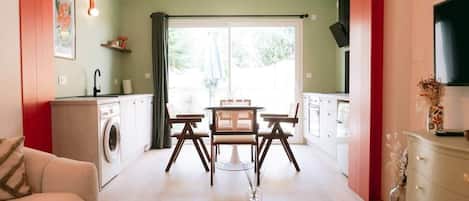 Un espacio habitable compacto con comedor, kitchenette y lavadora.