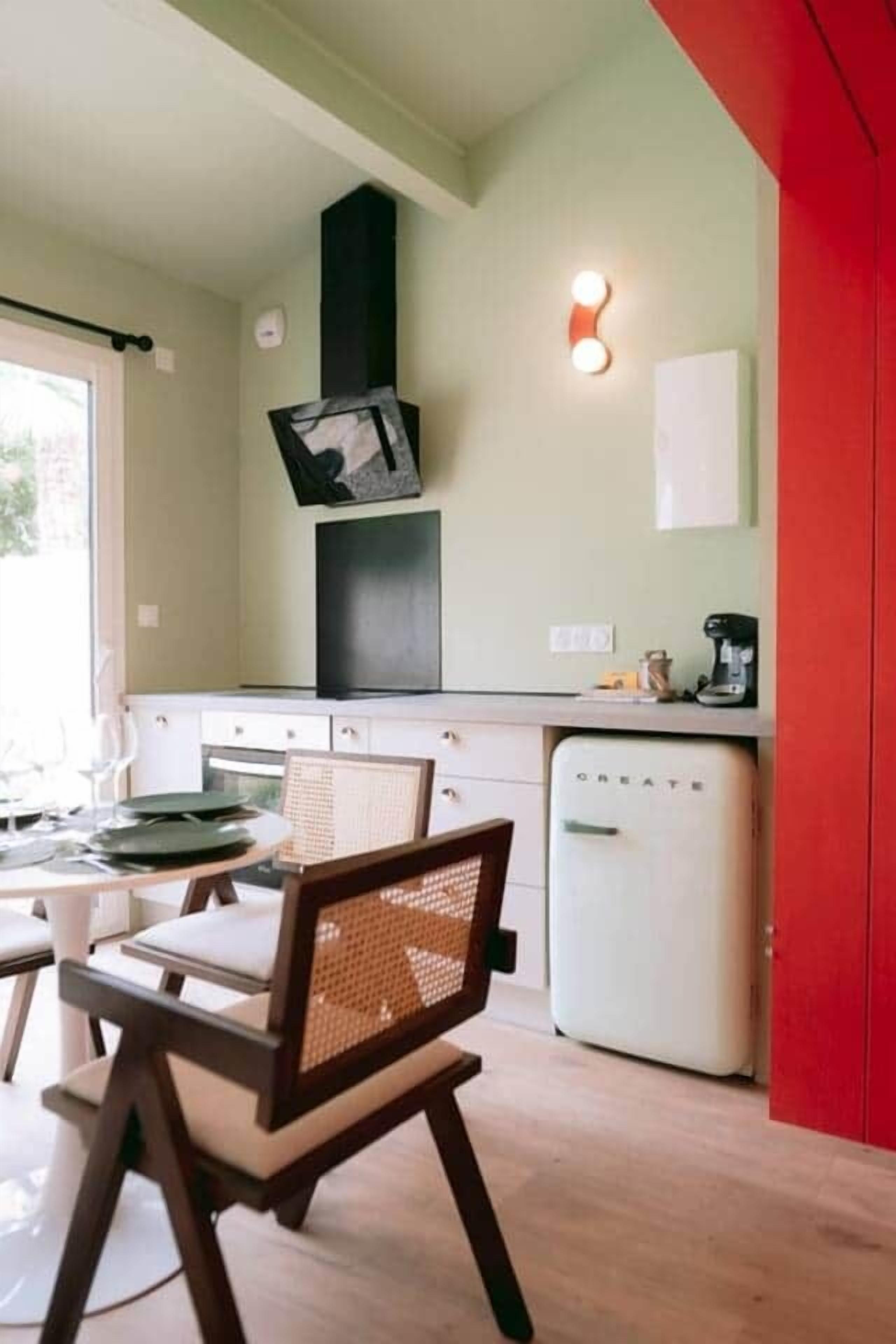 Une cuisine compacte avec un coin repas, un réfrigérateur blanc et un téléviseur fixé au mur.