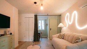 Un salon avec un canapé, un téléviseur, une lampe et une table.