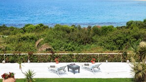 Eine Terrasse mit Blick auf das Meer, weiße Geländer und Gartenmöbel.