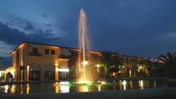 A building with a fountain in front, a pool, and palm trees. - Argo apartments near Nafplio (Nea Kios)