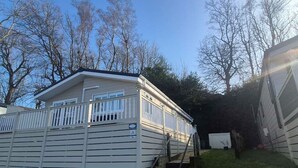 Une maison mobile dotée d’un porche à l’avant et d’un petit escalier menant à l’entrée.