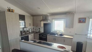Une cuisine moderne dotée d’un îlot central, d’appareils électroménagers intégrés et d’une fenêtre laissant entrer la lumière naturelle.