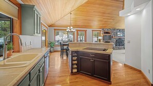 A modern kitchen with wooden ceiling, large windows, and a stone backsplash. - Quiet Sunriver Retreat with Access to Exclusive Golf (Sunriver)