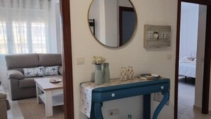A living room with a sofa, a coffee table, a blue console table with decorative items, a mirror, and a 'HOME' sign on the wall. - Vionta: Your cozy retreat with garden view near the beach (Aguiño)