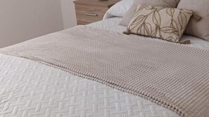 A neatly made bed with a quilted cover, a bedside table with a lamp, and a nightstand with drawers. - Vionta: Your cozy retreat with garden view near the beach (Aguiño)