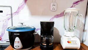 A kitchen with a slow cooker, a coffee maker, and a blender on a wooden countertop.
