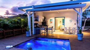Uma área de piscina moderna ao ar livre, com um espaço de estar coberto e um bar.