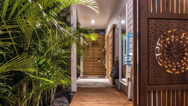 Um corredor de madeira com uma porta de madeira, um pequeno vaso com planta e um painel decorativo.
