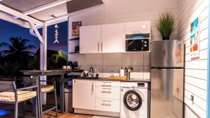 Cozinha compacta com máquina de lavar, micro-ondas e frigorífico.