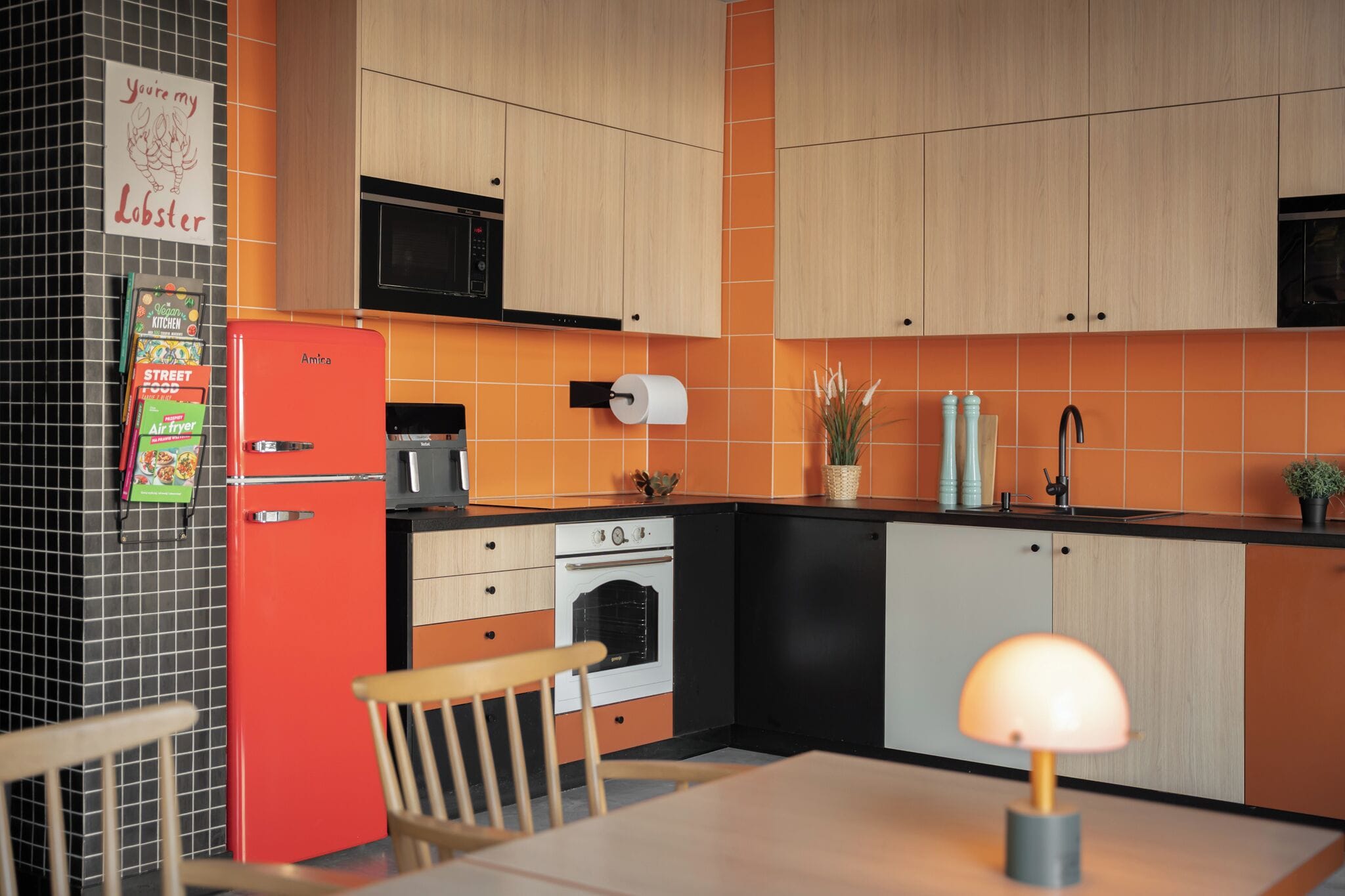 Une cuisine avec un réfrigérateur rouge, un four, un four à micro-ondes et un évier.