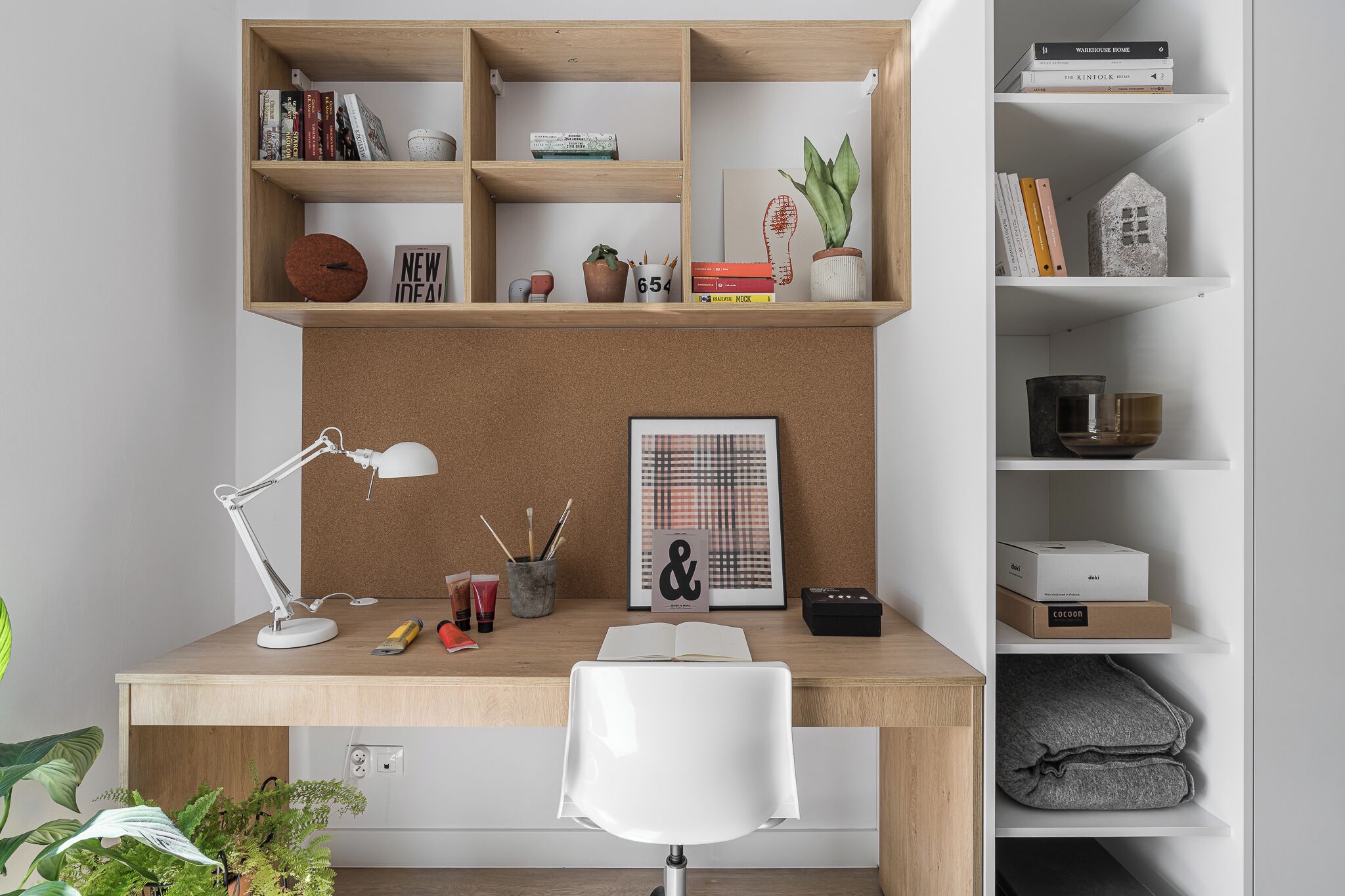 Un espacio de trabajo con escritorio, silla, estanterías y un tablón de anuncios.