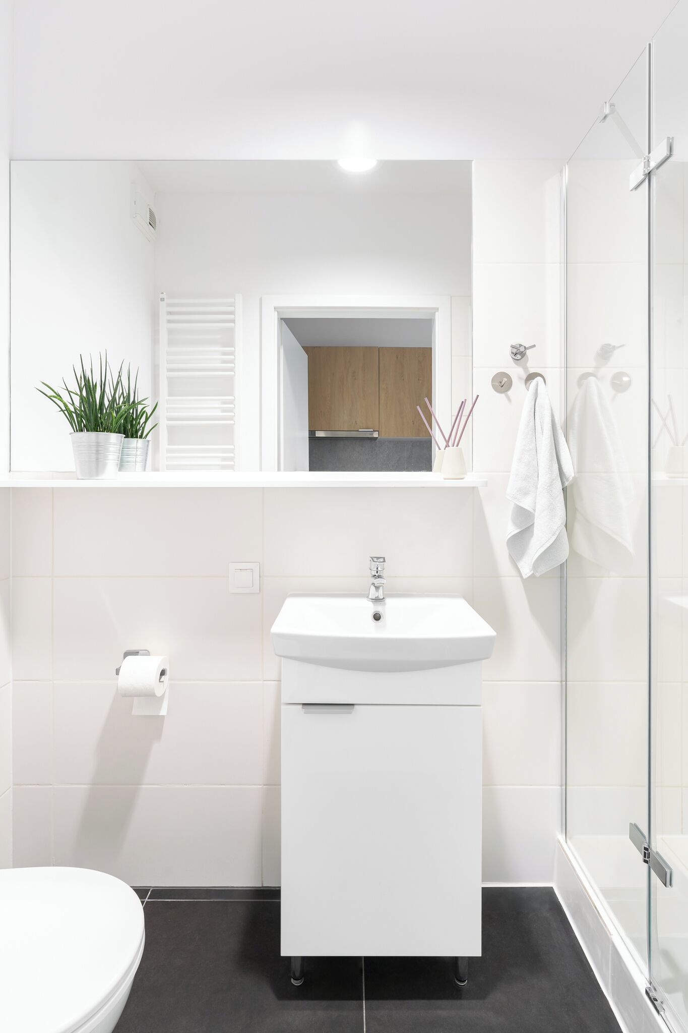 Een moderne badkamer met een wit wastafel, toilet en douche.