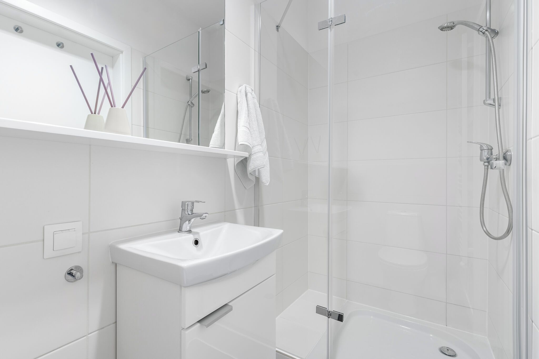 A modern bathroom with a white sink, mirror, and shower.
