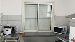 Una cocina con pileta, microondas, cafetera y olla de cocción lenta.