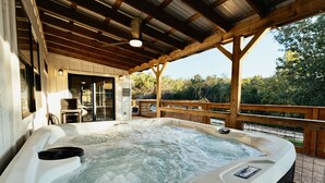 A hot tub under a wooden pergola with a view of trees. - Shangri-La, a spacious retreat at Wanderin’ Star Farms (Dripping Springs)