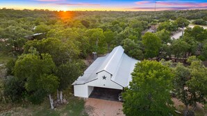 A single-story building with a metal roof and a star on the front, surrounded by dense greenery. - Shangri-La, a spacious retreat at Wanderin’ Star Farms (Dripping Springs)