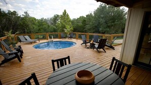 A wooden deck with a pool, lounge chairs, and a table. - Shangri-La, a spacious retreat at Wanderin’ Star Farms (Dripping Springs)