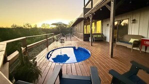 A wooden deck with a pool, outdoor furniture, and a building with a balcony.