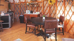 A cozy yurt with a round dining table, leather chairs, and a wooden interior. - Yurt in the trees w TX stars & Pickleball (Dripping Springs)