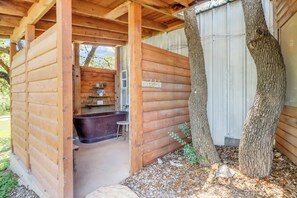 Een houten chalet met een houten terras, een badkuip en een klein raam.