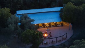 Ein Blick von oben auf ein Gebäude mit einer überdachten Terrasse, einer Feuerstelle und Sitzgelegenheiten im Freien.