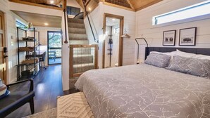 Ein Schlafzimmer mit einem großen Bett, einer Treppe, einem Schreibtisch und Blick ins Freie.