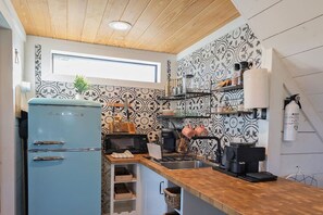 A compact kitchen with a blue Galanz refrigerator, a microwave, a coffee machine, and a sink. - Keep it Cozy, a secluded tiny home at Wanderin’ Star Farms (Dripping Springs)