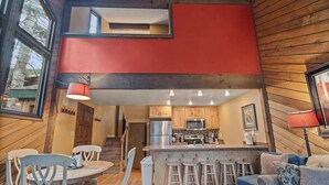 Eine moderne Küche mit Holzausstattung, einem Edelstahlkühlschrank und einer zentralen Kochinsel mit Sitzgelegenheiten.